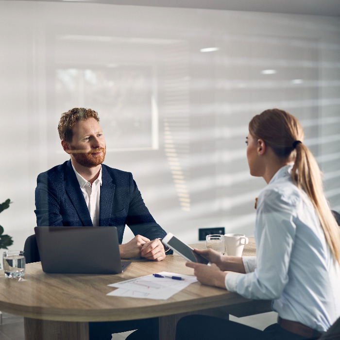 Man and woman facing each other over a table with paperwork